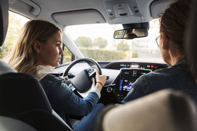 Teenage girl learning to drive from mother during weekend