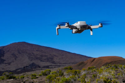 Low angle view of airplane flying against clear blue sky