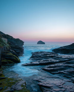 Scenic view of rocks in sea against clear sky