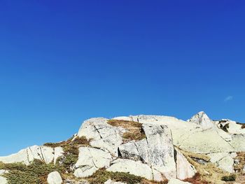 Low angle view of rock formation against clear blue sky