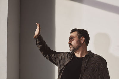 Mature man shielding eyes against wall