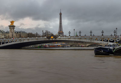 Bridge over river against cloudy sky