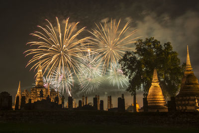 Firework display in city against sky at night