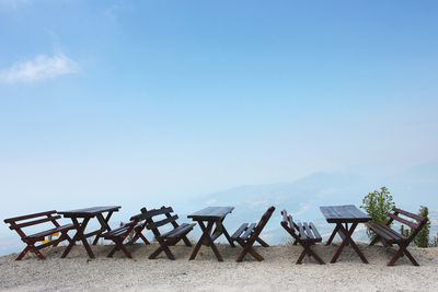 Empty chairs and tables against clear blue sky