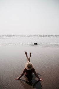 Full length of young woman on beach against clear sky