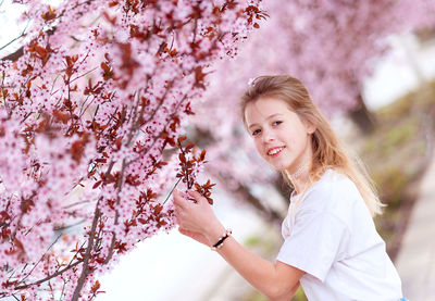 Portrait of smiling young woman sitting on tree