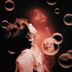 Close-up of boy amidst bubbles against mirror