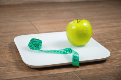 Scale with measuring tape on white scales. weight loss concept. fresh apple and measuring tape on