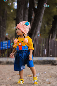 Portrait of cute little girl wearing hat standing at beach