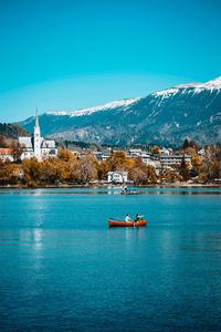 Scenic view of sea and snowcapped mountain against blue sky