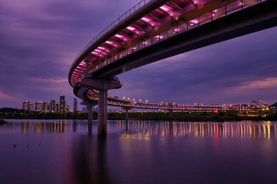 Illuminated bridge over river against sky at night