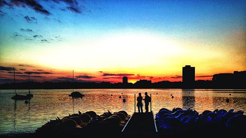 Silhouette of people in river at sunset