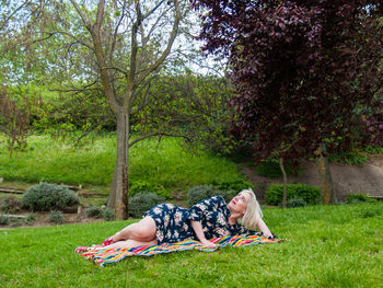 Mature woman lying on picnic blanket at park