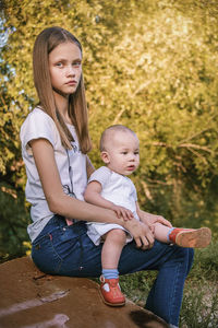 Full length of mother and girl sitting outdoors