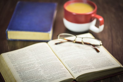 High angle view of books with eyeglasses and drink on table