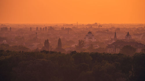 Panoramic view of trees and buildings against sky during sunset