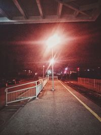 Illuminated road against sky at night