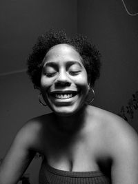 Close-up of happy young woman against black background