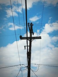 Low angle view of electricity pylon against cloudy sky