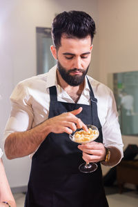 Side view of young man holding food at home