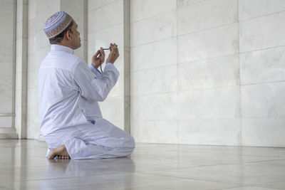 Rear view of man praying in mosque