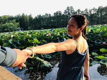 Cropped image of friend holding woman hand against plants