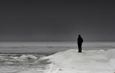 Full length of man standing at frozen sea during winter