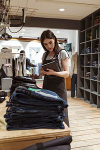 Saleswoman using digital tablet while checking purchase order at boutique