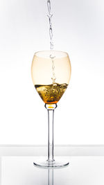 Close-up of wineglass on glass against white background