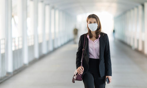 Businesswoman wearing mask standing on footbridge