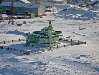 High angle view of snow covered field by buildings