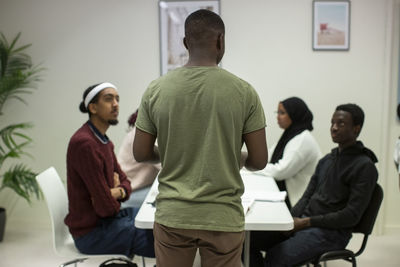 Rear view of male teacher teaching multiracial students in classroom