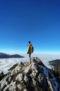 Man standing on rock against sky