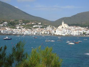 Lake with boats by houses against mountain