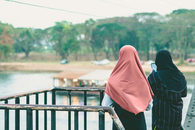 Rear view of women standing against railing