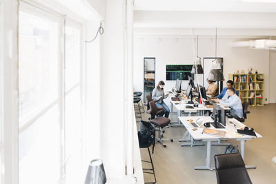 High angle view of male and female it professionals working at desks in office