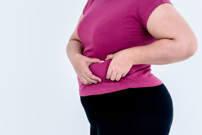 Midsection of woman touching hair against white background