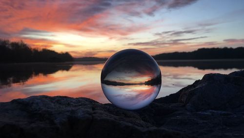 Reflection of rocks in lake against sky during sunset