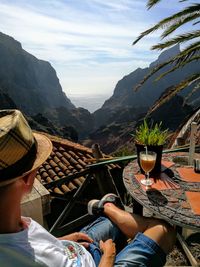 Man with drink on table against sky