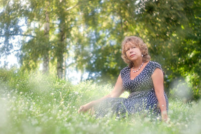 Thoughtful senior woman sitting on grass