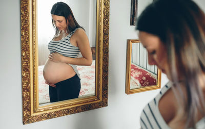 Young woman standing by mirror