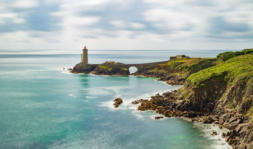 Lighthouse by sea against sky