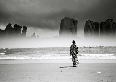 Woman walking on beach against built structures