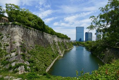 Buildings by river against sky