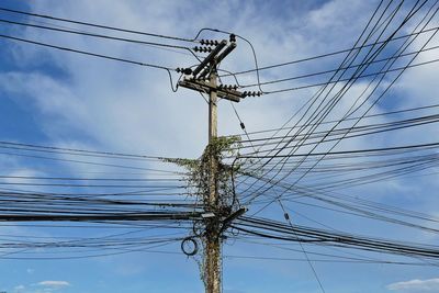 Low angle view of electricity pylon against blue sky