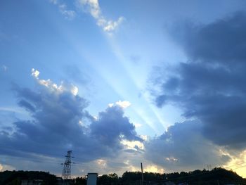 Low angle view of sunlight streaming through clouds