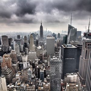 Aerial view of modern buildings in manhattan against cloudy sky