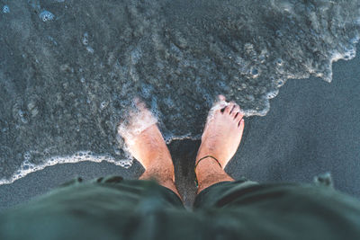 Low section of man standing on beach