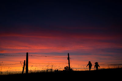 Silhouette people standing on field against sky during sunset