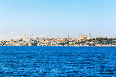 Scenic view of sea and cityscape against clear sky